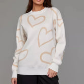 White sweater with beige heart patterns worn by a person